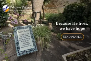 Scripture sign in the Garden Tomb garden in Jerusalem, surrounded by plants and ancient stone walls
